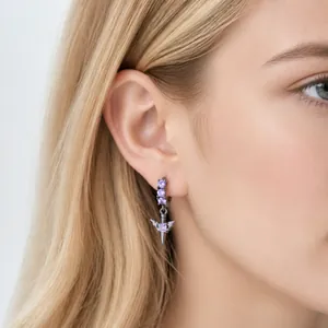 Dunkle Gothic Schwert Kreuz Ohrringe mit lila Steinen an einem silberhaarigen Model