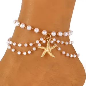 Detail van gelaagde enkelband met imitatieparels en een goudkleurige zeester hanger
