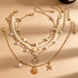 Detailopname van een vierdelige gelaagde enkelbandset met schelp- en zeesterbedels van goud