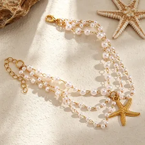 Gedetailleerd beeld van drielaagse parelen enkelband met gouden zeester-hanger