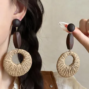 Detailed view of bohemian raffia woven round earrings with dark wood beads and textures.