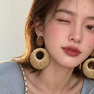 Detailed shot of a model wearing large bohemian woven raffia circular drop earrings