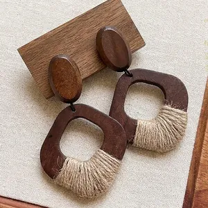 Detail of Bohemian dark wood earrings with raffia woven accents and natural texture.