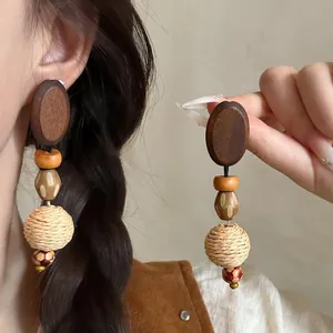 Macro view of bohemian raffia woven earrings featuring wooden beads and oval studs