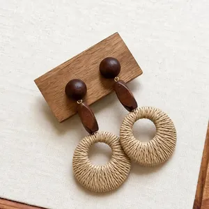 Macro detail of bohemian style raffia woven round earrings with dark wooden beads accents.