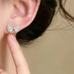 Close-up view of exquisite silver-colored bow-knot stud earring worn on the earlobe.