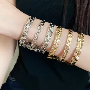 Detalle de brazaletes de metal arrugado con textura martillada irregular en el brazo