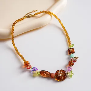 Gros plan du collier vintage avec perles d'ambre et breloques de fleurs colorées.