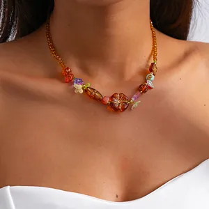 Détail d'un collier vintage en verre ambré avec des perles de fleurs colorées