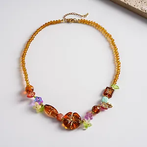 Détail d'un collier vintage avec perles de verre ambrées et breloques fleurs en acrylique