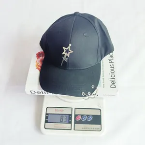 Dettaglio del peso di un cappello da baseball nero con ciondolo a stella e anelli.