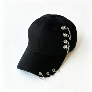 Dettaglio di cappello da baseball nero con anelli di metallo punk e catene laterali.