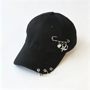 Dettaglio cappellino nero con anelli in metallo e spilla da balia con ciondoli a stella