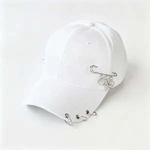 Dettaglio cappello bianco con anelli metallici sulla visiera e spilla decorativa