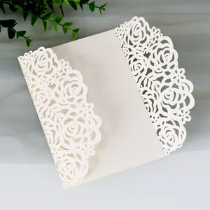 Vista dettagliata dell'elegante invito di nozze bianco tagliato al laser con rose in carta perlata.