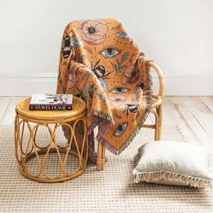 Detailed view of bohemian woven throw blanket featuring bee patterns on a rattan chair