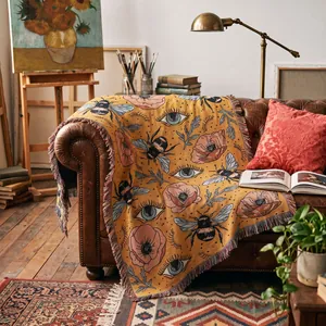 Detailed view of a Bohemian woven throw blanket with bee and floral patterns on a sofa.