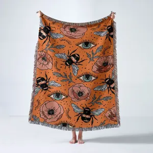 Full view of bohemian bumblebee woven blanket held up against a neutral background