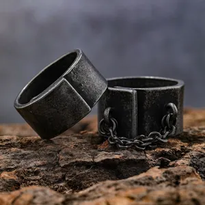 Retro punk style men's wide band ring set with metal chain detail on textured wood