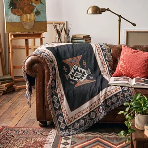 A cozy bohemian throw blanket with tassels draped over a vintage leather sofa