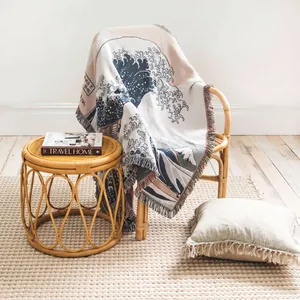 Detailed view of bohemian woven throw blanket with Great Wave art draped on rattan chair
