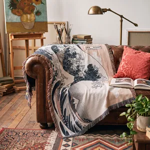 Detailed shot of a woven throw blanket featuring Hokusai's Great Wave art on a leather sofa.
