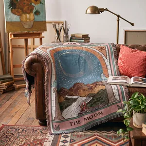 Détail d'une couverture tissée bohème avec le motif du tarot 'La Lune' sur un canapé.