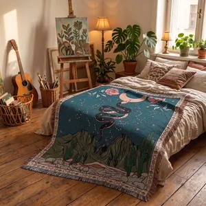 Woven bohemian throw blanket with snake and moon desert landscape on a cozy bed.