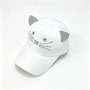 Detailansicht einer weißen Baseballkappe mit funkelnden Katzenohren und Gesicht aus Strass.