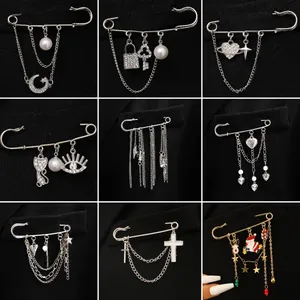 Collection of punk style safety pin brooches with charms and chains on a black suit lapel.
