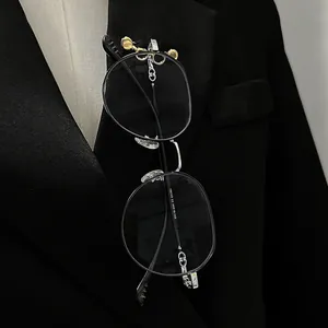 Detailed close-up view of the CD logo brooch holding black glasses on a black suit lapel