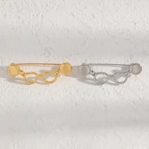 Detailed close-up of minimalist glasses-shaped brooches in elegant gold and silver finishes