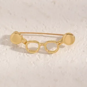 Close-up of a unique gold glasses shaped brooch with a polished metallic finish