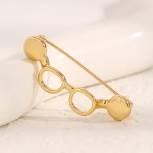 Close-up of a gold glasses-shaped brooch with minimalist hollow circular design