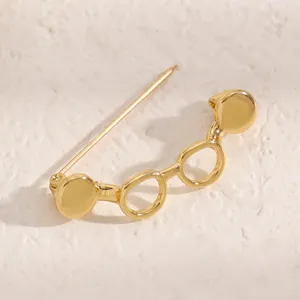 Detailed macro view of a minimalist gold-toned glasses-shaped decorative lapel pin brooch