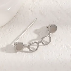 Close-up detail shot of a silver glasses-shaped brooch with hollow circular design.