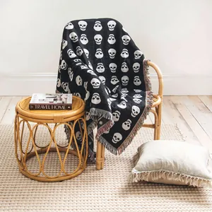 Détail d'une couverture tissée noire et blanche à motif tête de mort avec franges.