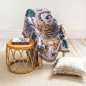 Couverture tissée bohème avec motif artistique de tigre et feuilles sur une chaise en rotin