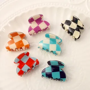 Detail view of six colorful checkerboard mini claw hair clips arranged on white plate