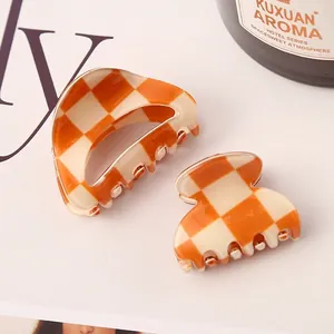 Detailed view of orange and beige checkered hair claw clips with acetate-like finish