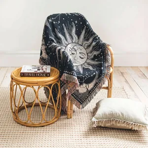 Coperta tessuta in stile boho con motivo sole e luna su una poltrona in rattan accogliente