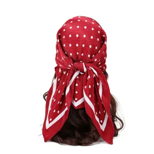 Vue détaillée arrière d'un foulard en satin plissé rouge à pois noué sur une tête.