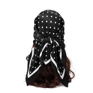 Détail arrière d'un foulard en satin noir plissé à pois blancs noué sur les cheveux