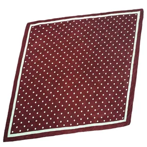 Gros plan détaillé d'un foulard carré en satin plissé bordeaux à motifs de petits pois blancs.