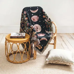 Close-up of bohemian moon phase woven throw blanket draped over a stylish rattan chair