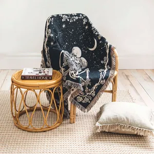 Bohemian skeleton and celestial pattern woven throw blanket with fringe detail on a chair