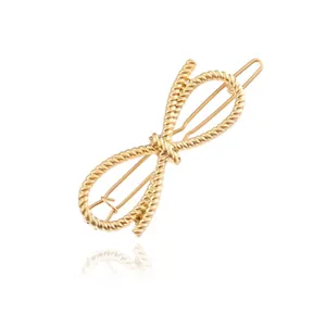 Detail view of a gold-colored twisted rope bow hair clip with a metallic texture.