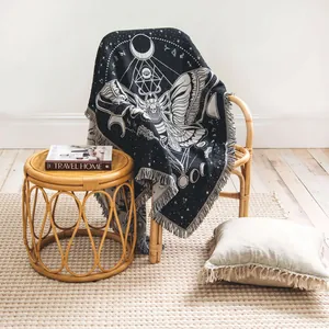 Mystical moth and moon phase cotton woven throw blanket on a stylish rattan chair