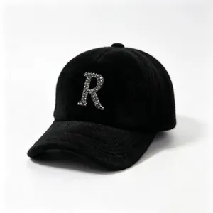 Detailed view of black fuzzy baseball cap with sparkling rhinestone letter R emblem.