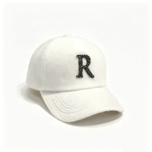 Stylish white plush baseball cap featuring a decorative rhinestone letter R on the front.